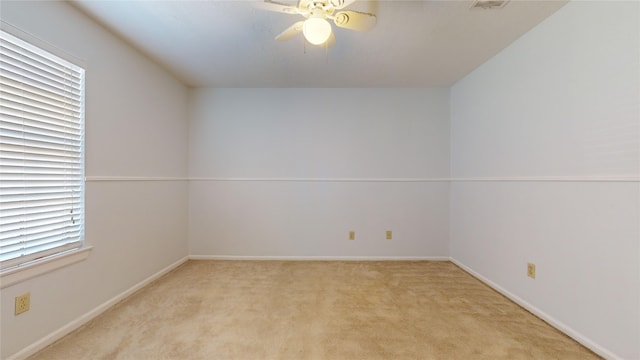 carpeted empty room with ceiling fan and a wealth of natural light