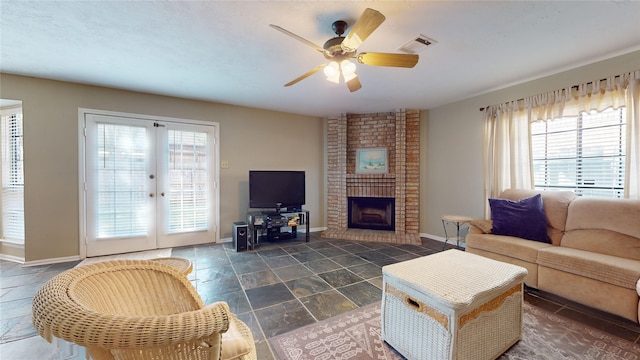 living room with ceiling fan, french doors, and a brick fireplace