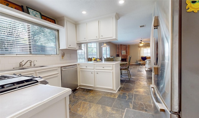 kitchen with kitchen peninsula, appliances with stainless steel finishes, ceiling fan, sink, and white cabinets