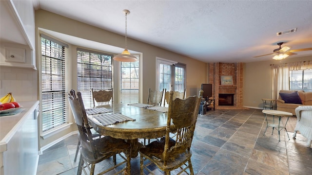 dining space with a fireplace, ceiling fan, and a healthy amount of sunlight