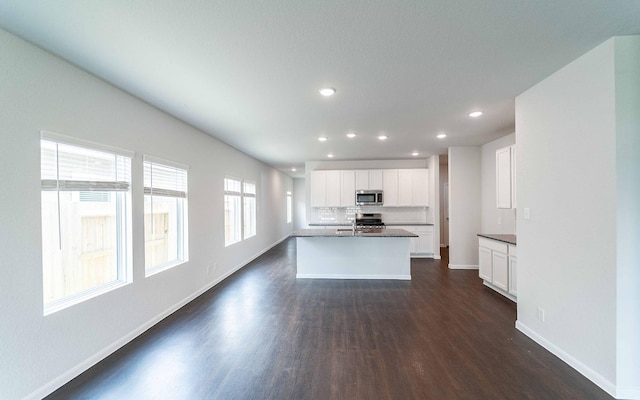 4315 Maple Root Ln, Pinehurst, TX 77362 - kitchen with stainless steel appliances, dark wood-style floors, white cabinets, recessed lighting, and a center island with sink