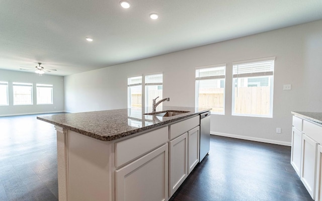 4315 Maple Root Ln, Pinehurst, TX 77362 - kitchen with stainless steel dishwasher, ceiling fan, dark stone countertops, a center island with sink, and white cabinetry