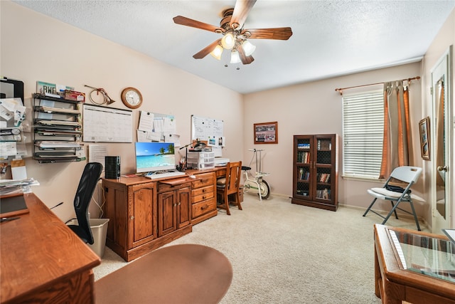 carpeted office featuring ceiling fan and a textured ceiling