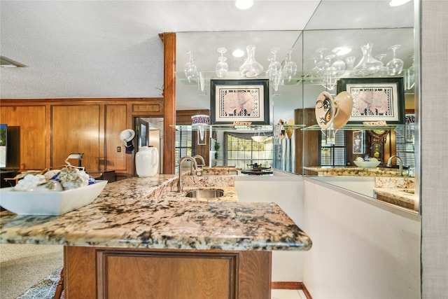 kitchen featuring wood walls, a textured ceiling, sink, and kitchen peninsula