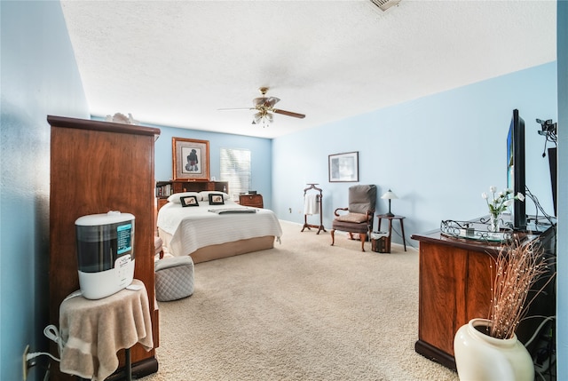 bedroom featuring ceiling fan, a textured ceiling, and light colored carpet