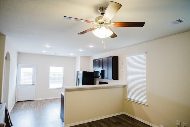 kitchen featuring black fridge, ceiling fan, kitchen peninsula, and dark wood-type flooring