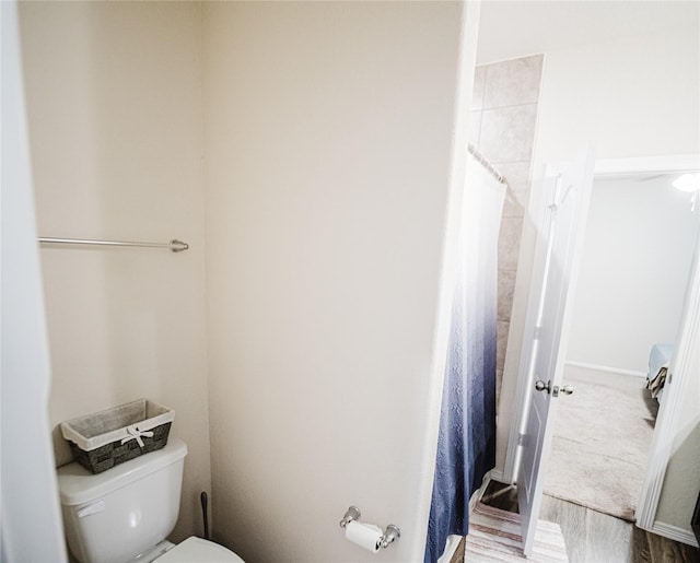 bathroom with hardwood / wood-style floors, a shower with curtain, and toilet