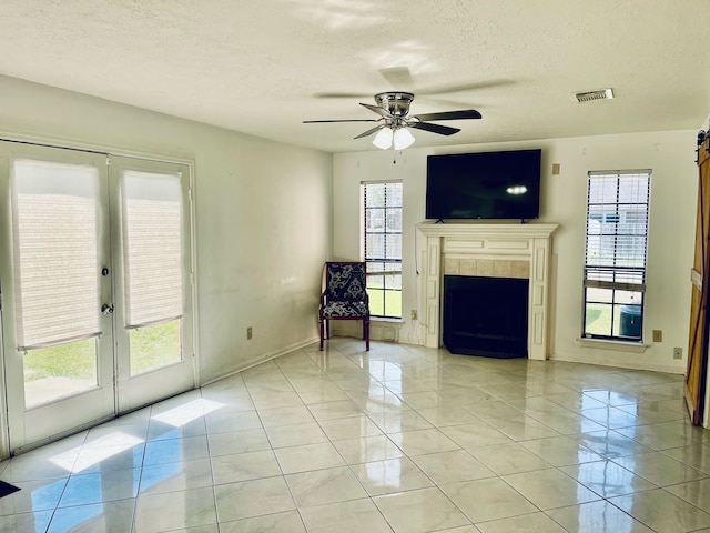 unfurnished living room featuring ceiling fan, a textured ceiling, light tile patterned floors, and plenty of natural light