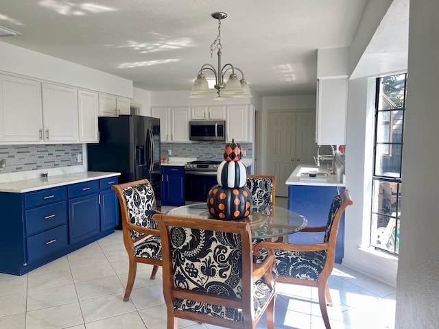 kitchen featuring a notable chandelier, pendant lighting, white cabinetry, blue cabinetry, and appliances with stainless steel finishes