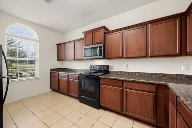 kitchen featuring electric range, dark stone countertops, and light tile patterned floors