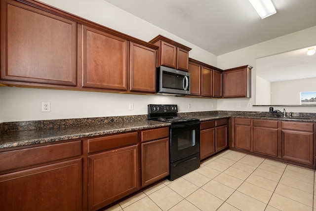 kitchen with light tile patterned floors, black / electric stove, dark stone countertops, and sink