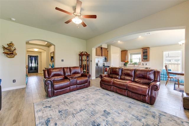 living room featuring light hardwood / wood-style floors, ceiling fan, and vaulted ceiling