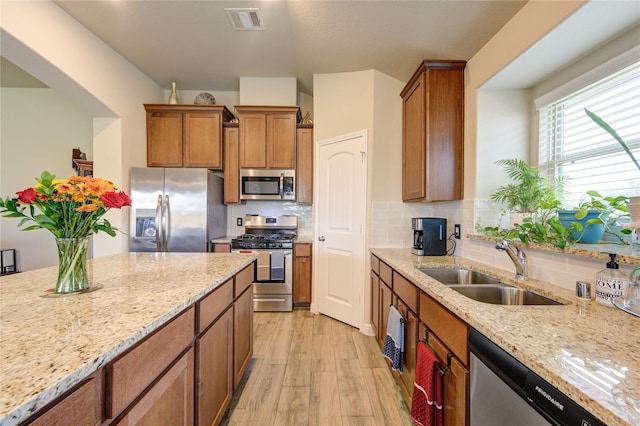 2446 Wembley Way, Rosenberg, TX 77471 - kitchen with stainless steel appliances, a sink, light wood-type flooring, and light stone countertops