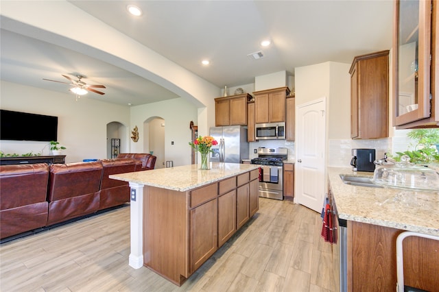 kitchen with light stone countertops, stainless steel appliances, and light hardwood / wood-style floors