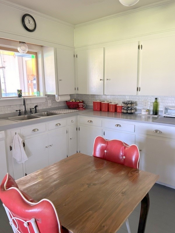 kitchen featuring white cabinetry, backsplash, stainless steel counters, and sink