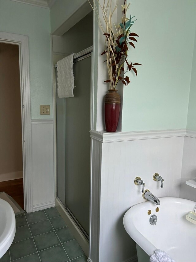 bathroom with a shower with door, ornamental molding, and tile patterned flooring