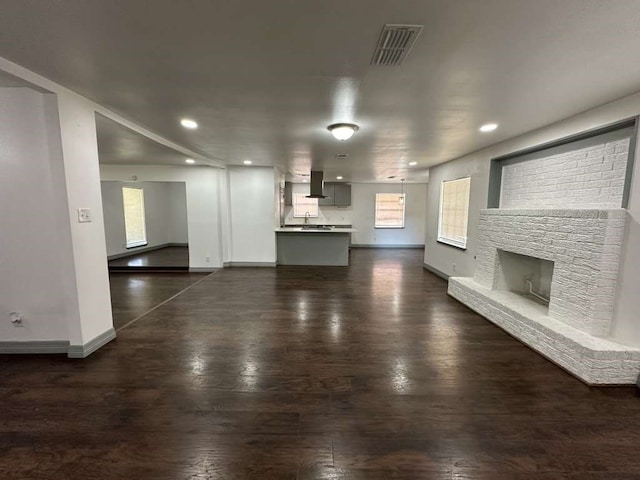 unfurnished living room featuring dark hardwood / wood-style flooring and a wealth of natural light