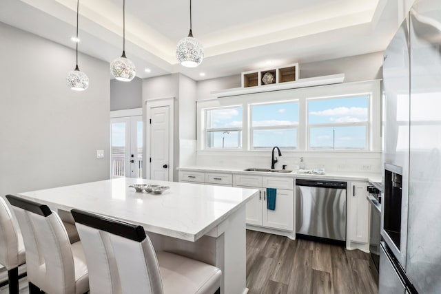 kitchen featuring pendant lighting, dark wood-type flooring, sink, appliances with stainless steel finishes, and white cabinetry