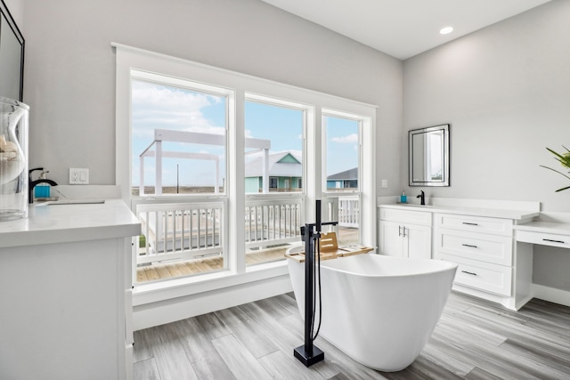 bathroom with a tub to relax in, vanity, and hardwood / wood-style flooring