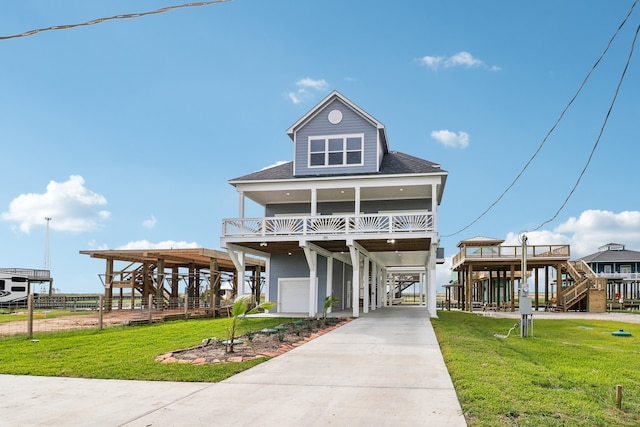 beach home featuring covered porch, a front lawn, a carport, and a garage