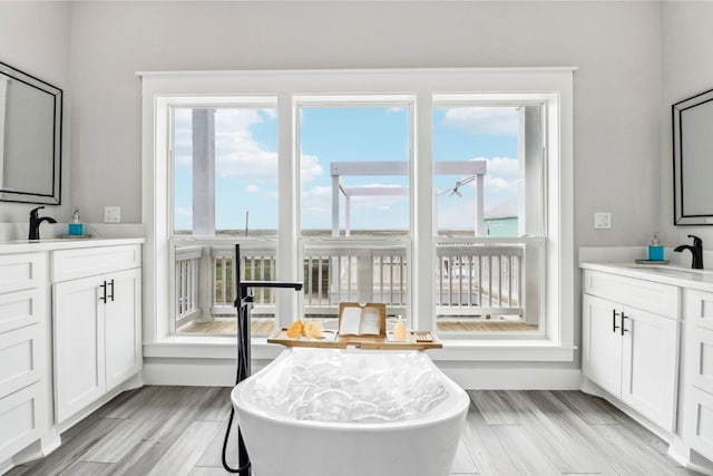 555 Pompano Dr Unit Q, Freeport, TX 77541 - full bathroom featuring wood finished floors, two vanities, a soaking tub, and a sink