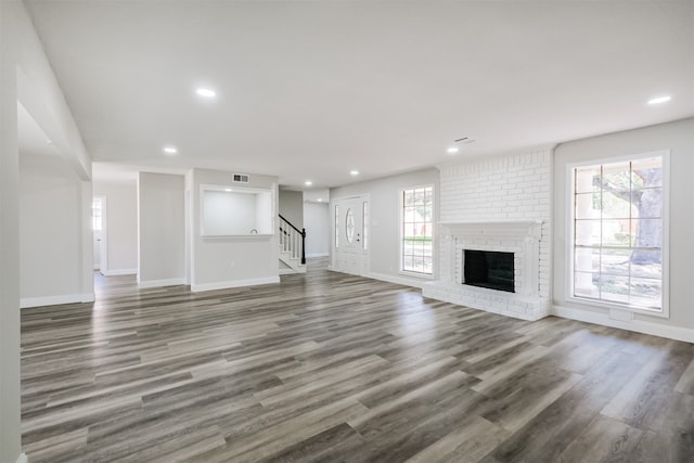 unfurnished living room featuring dark hardwood / wood-style flooring, a fireplace, and a wealth of natural light