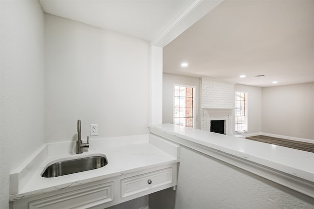 interior space featuring light stone countertops, sink, white cabinetry, and a fireplace