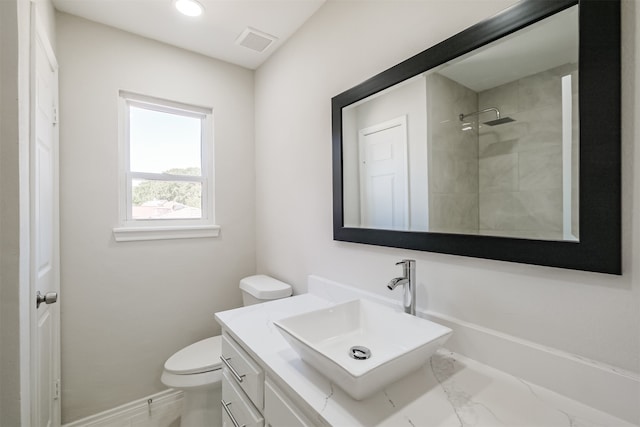 bathroom with vanity, toilet, and a tile shower