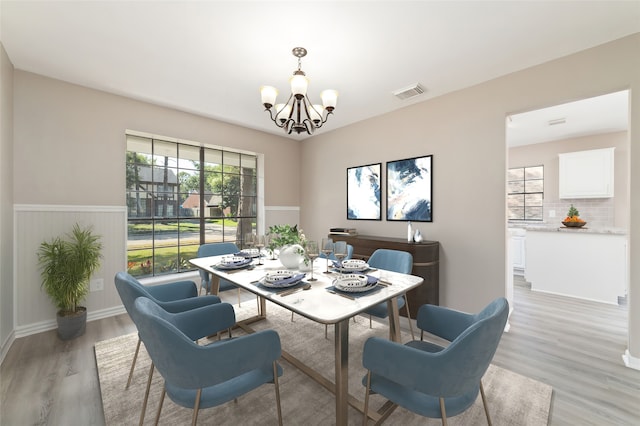 dining area with light hardwood / wood-style floors and an inviting chandelier