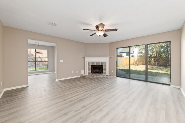 unfurnished living room featuring light hardwood / wood-style flooring, a brick fireplace, and ceiling fan