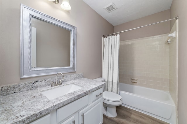 full bathroom featuring hardwood / wood-style floors, a textured ceiling, toilet, shower / bath combo with shower curtain, and vanity