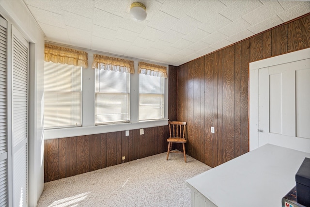 carpeted home office with wood walls