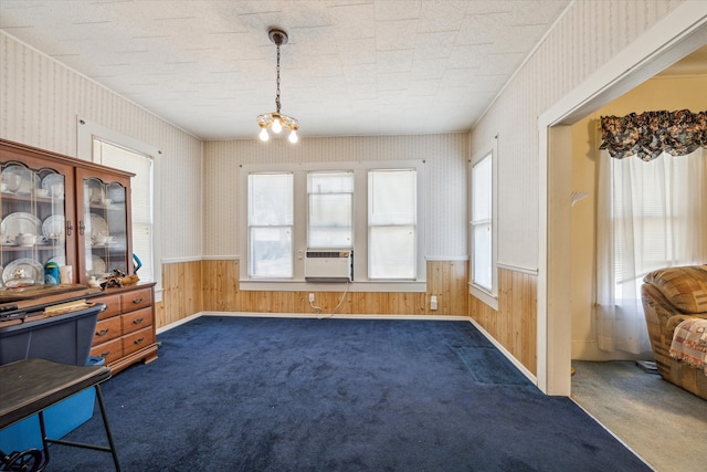 dining area with a textured ceiling, cooling unit, wooden walls, dark carpet, and an inviting chandelier