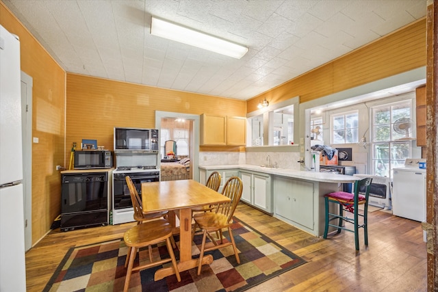 kitchen featuring washer / dryer, black appliances, light wood-type flooring, and a kitchen island