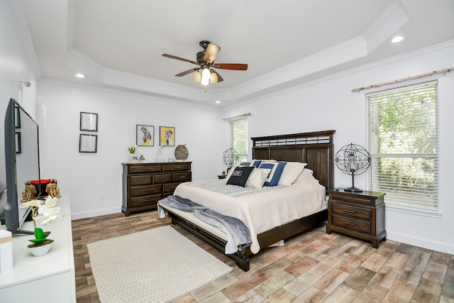 bedroom featuring light wood-type flooring, a raised ceiling, and multiple windows