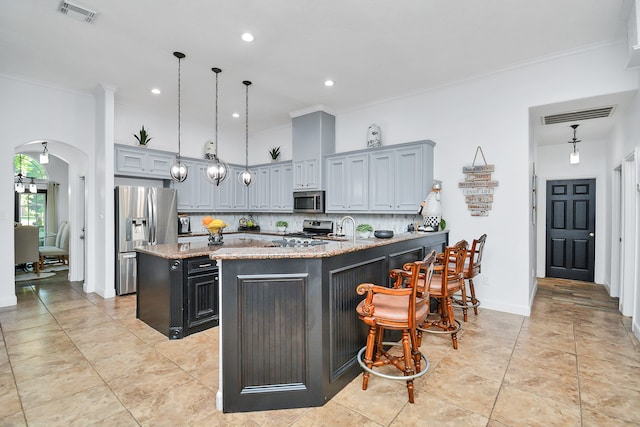 kitchen with light stone counters, ornamental molding, appliances with stainless steel finishes, decorative light fixtures, and backsplash