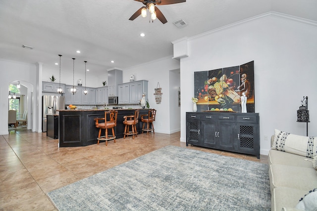 tiled living room featuring ceiling fan, crown molding, and vaulted ceiling