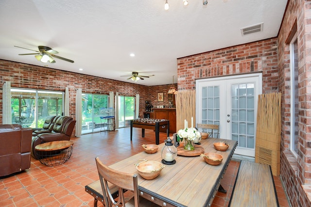 tiled dining room featuring french doors, brick wall, a textured ceiling, and ceiling fan