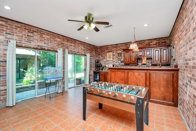 playroom featuring light tile patterned floors, ceiling fan, beverage cooler, and brick wall