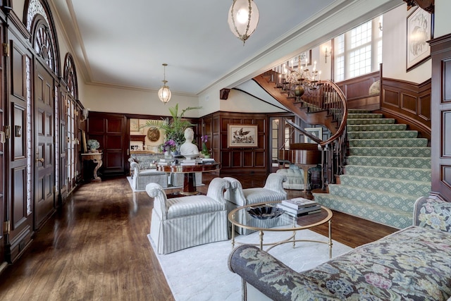 living room with an inviting chandelier, ornamental molding, dark wood finished floors, and stairs