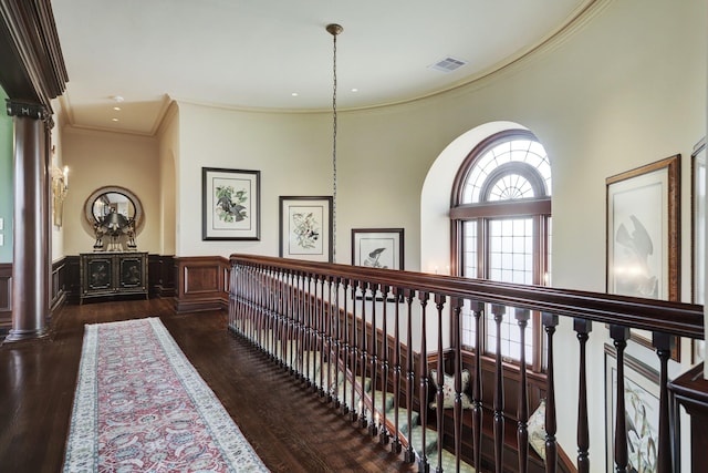 hall featuring visible vents, wainscoting, wood finished floors, and crown molding
