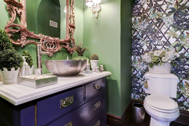half bath featuring toilet, vanity, and baseboards