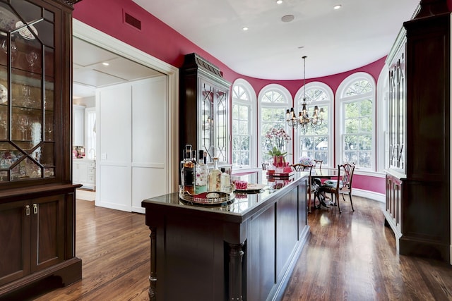 kitchen featuring pendant lighting, visible vents, dark brown cabinetry, dark wood-type flooring, and a notable chandelier