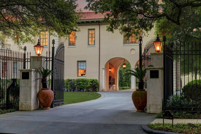 mediterranean / spanish house featuring driveway, stucco siding, a gate, and fence