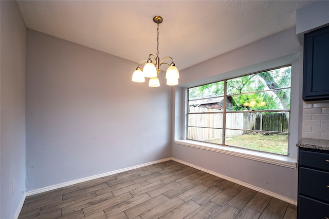 unfurnished dining area featuring a wealth of natural light, an inviting chandelier, and light hardwood / wood-style floors