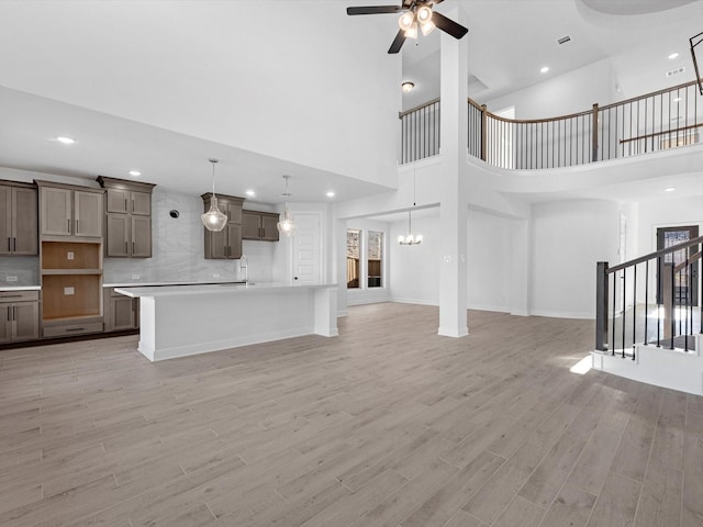 unfurnished living room with a high ceiling, light hardwood / wood-style flooring, and ceiling fan