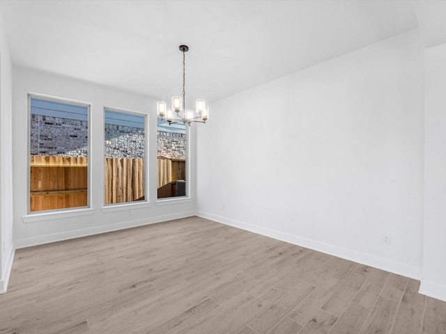 unfurnished dining area with light hardwood / wood-style floors and an inviting chandelier