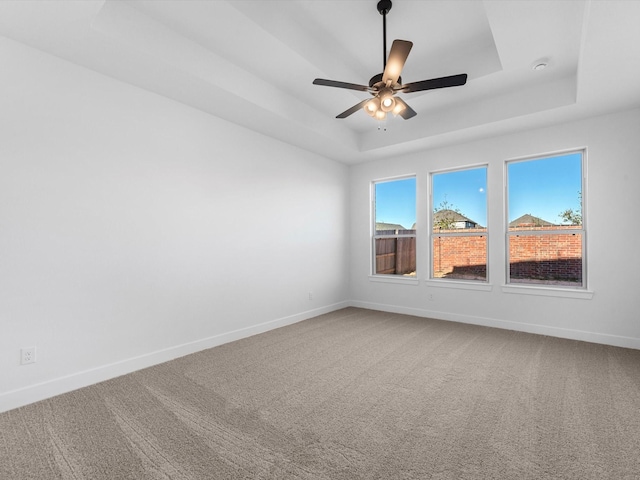 empty room with carpet, a tray ceiling, and ceiling fan