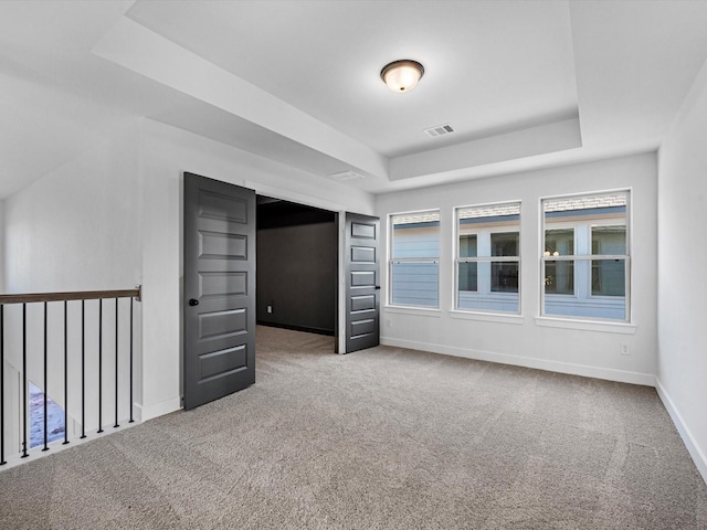 unfurnished bedroom with a raised ceiling and carpet floors