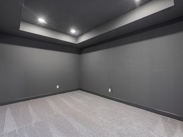 empty room featuring carpet and a raised ceiling